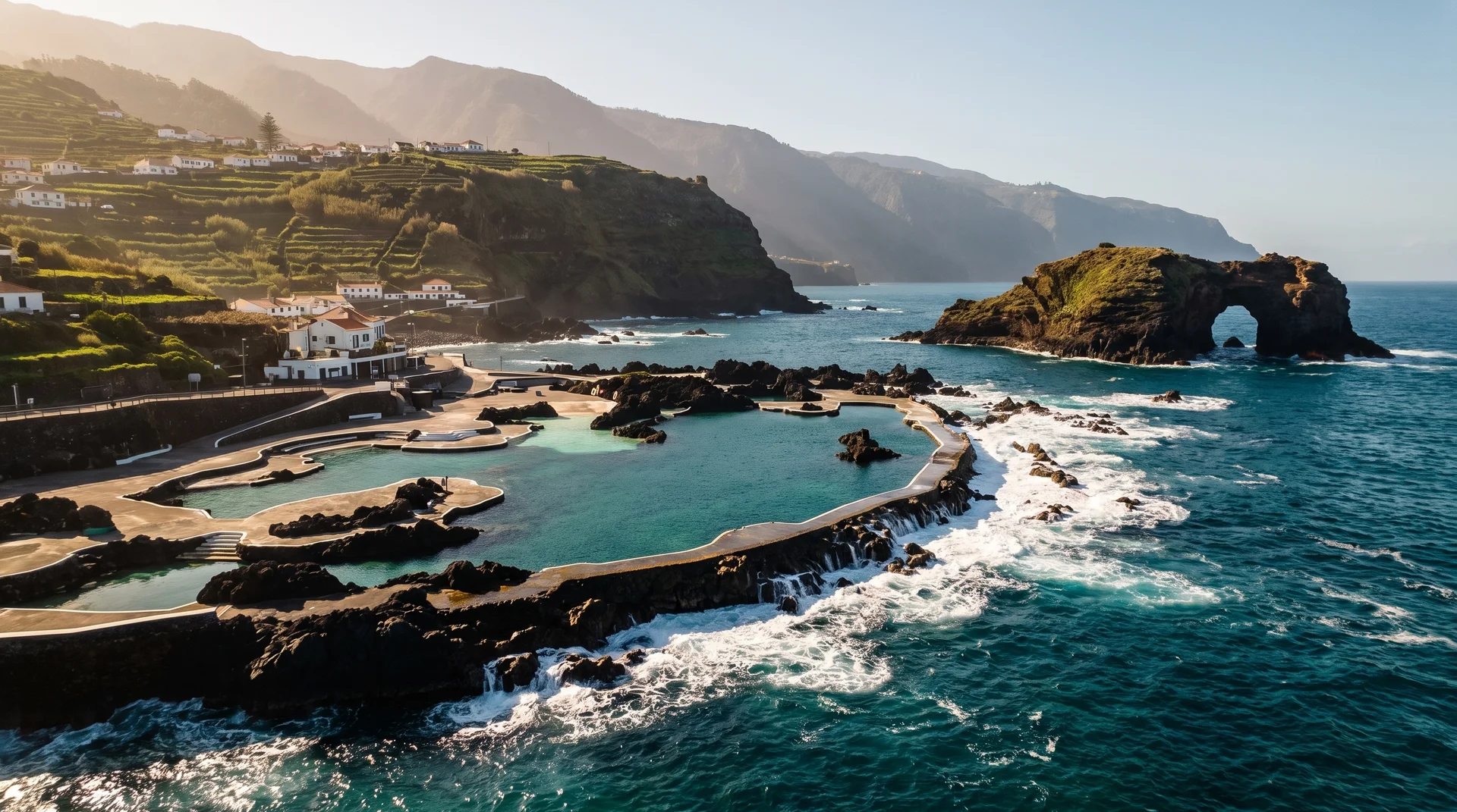Volcanic lava-rock bathing pools at Porto Moniz with the Ilheu Mole arch offshore, Madeira